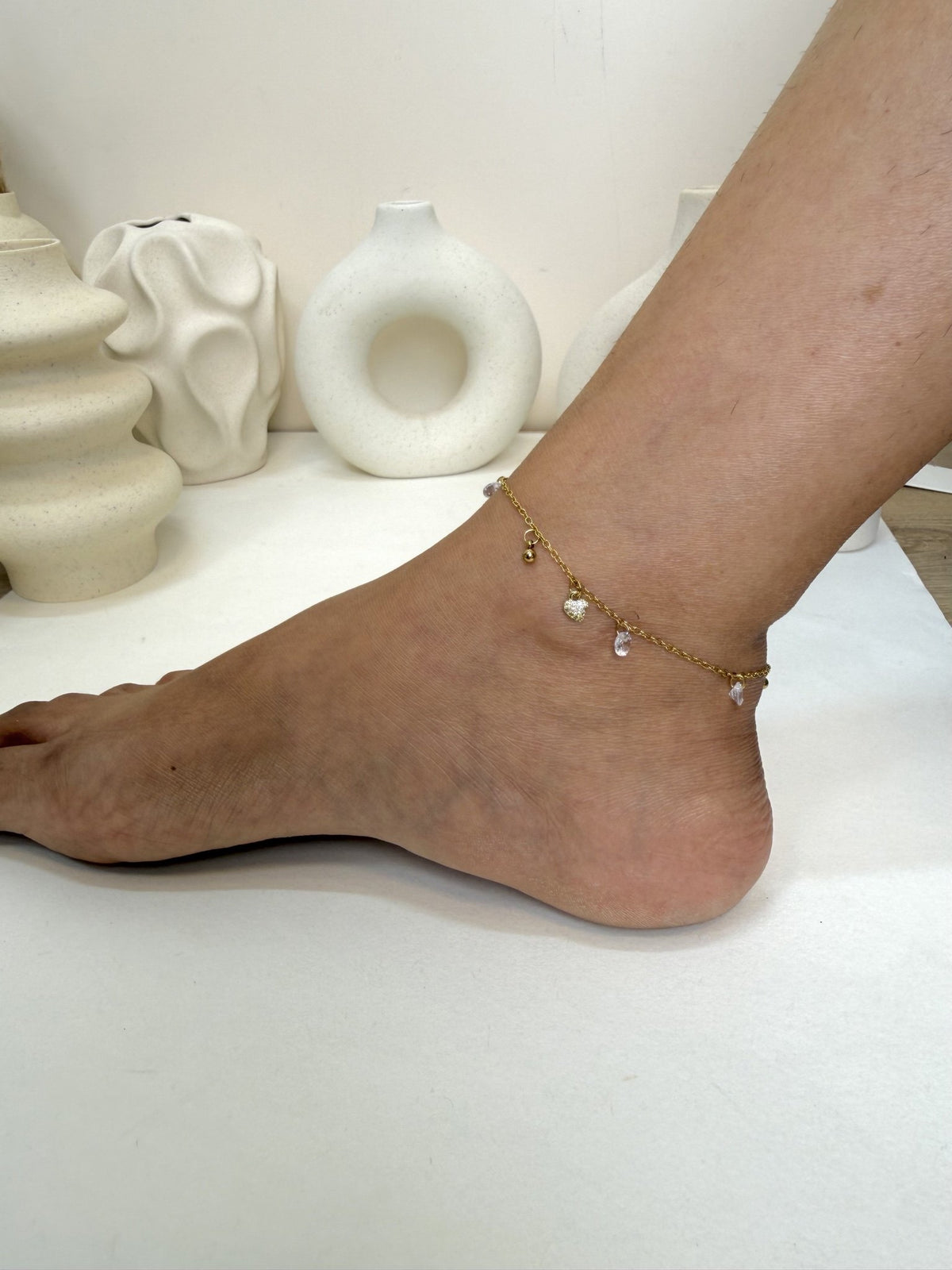 Paired Lunelle Anklet in gold-tone, worn on the ankle with a dainty chain and small clear drop stones