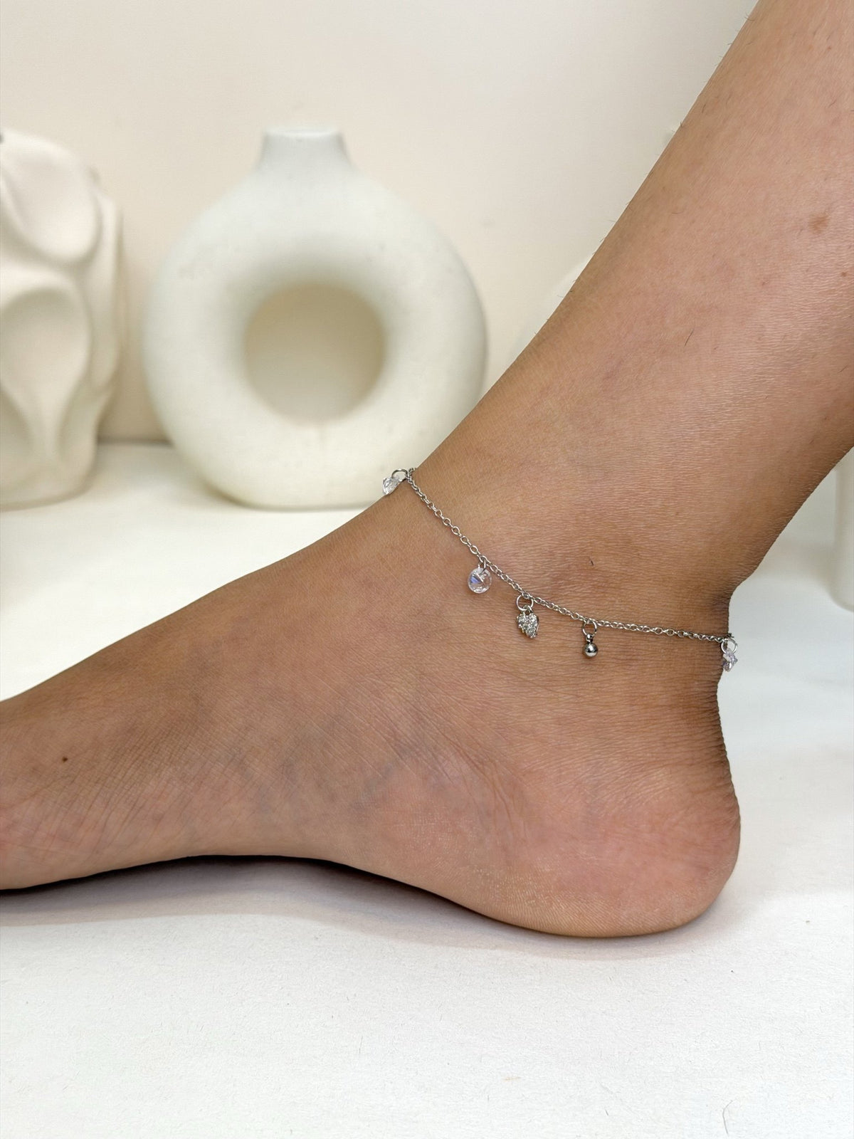Paired Lunelle Anklet in silver-tone, side view on the ankle with small clear drop stones along the chain