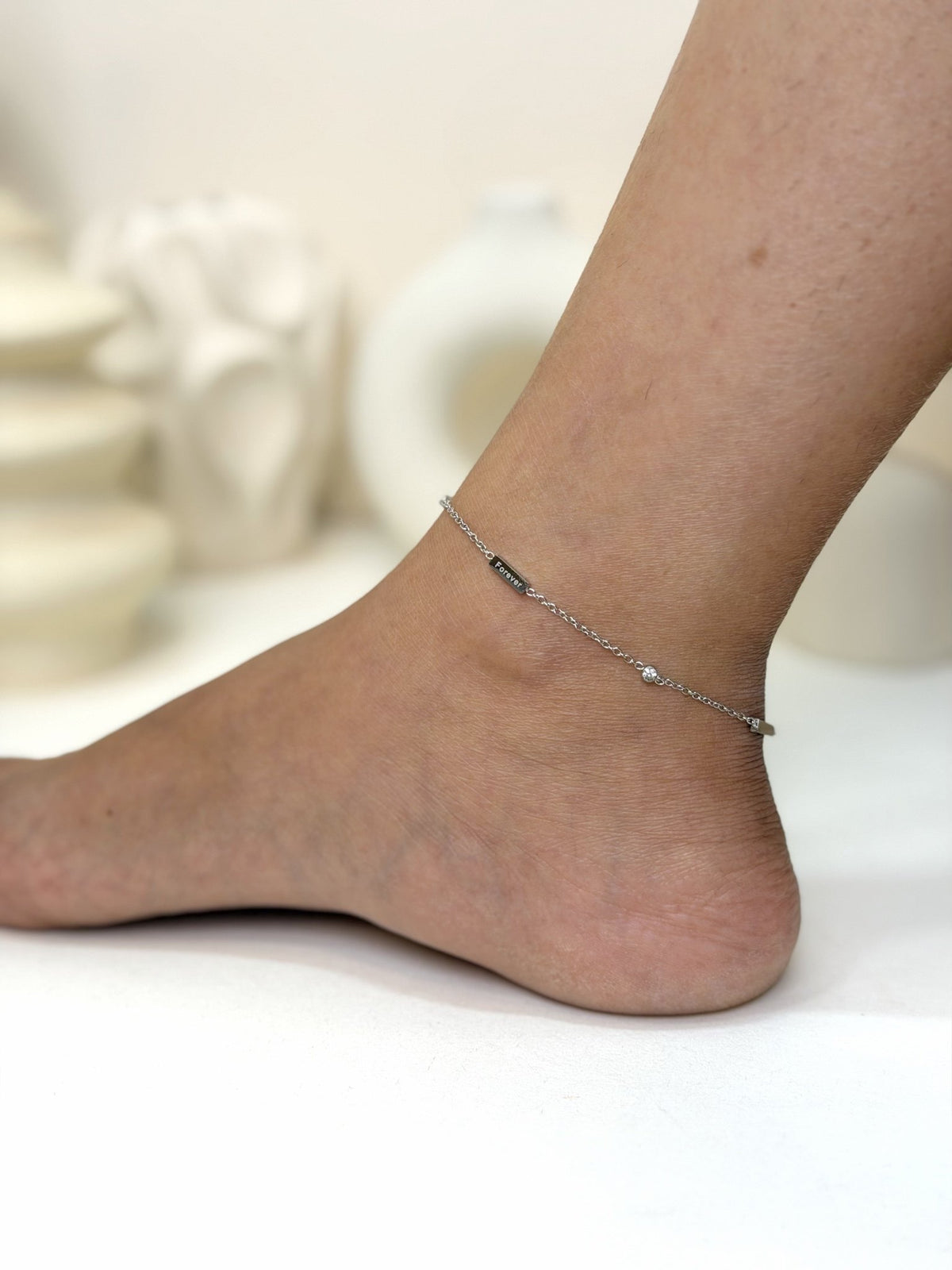 Paired Marielle Anklet in silver-tone, side view on the ankle with a fine chain and black bar detail