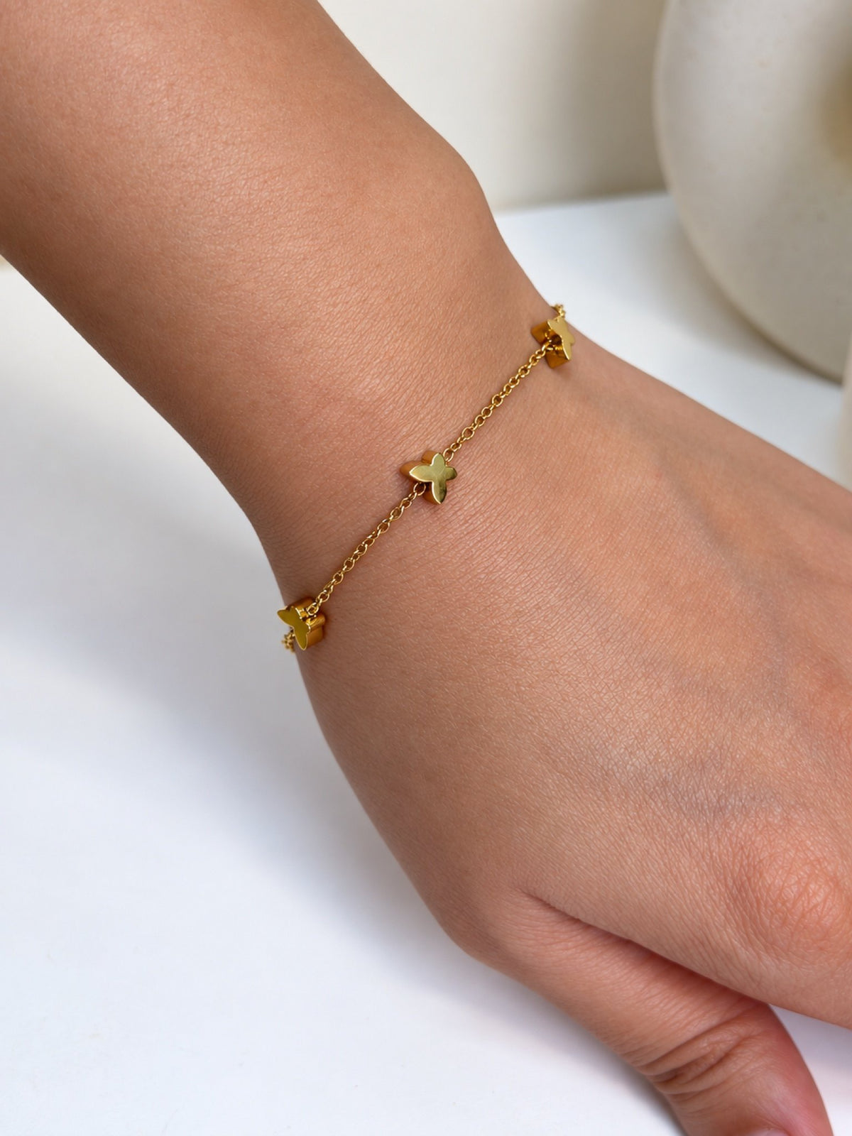 Paired Nerelia Bracelet in gold-tone, close view on the wrist showing small butterfly charms on a fine chain
