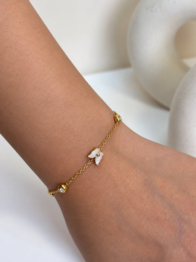 Paired Nerisse Bracelet in gold-tone, close view on the wrist showing a white butterfly charm, beads and a clear stone
