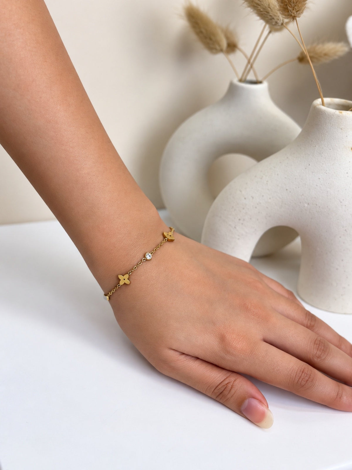 Paired Nolia Bracelet in gold-tone, worn on the hand with a four-point star charm and small clear stones on a fine chain