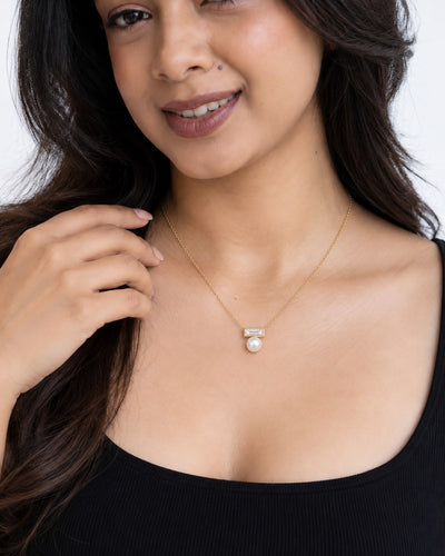Paired Radiant Love Chain in gold-tone, worn close-up: clear baguette crystal bar with a centred white pearl drop