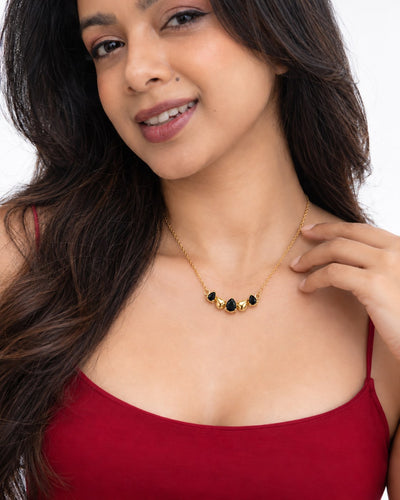 Paired Raven Drops Chain in black, worn close-up with black pear stones and gold-tone teardrops on a fine chain