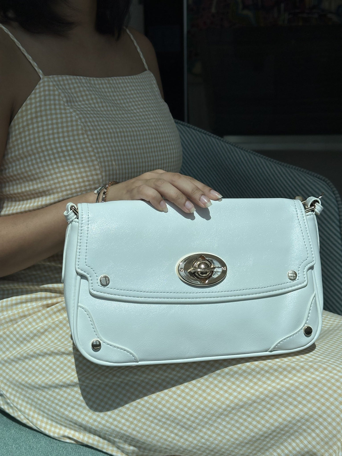 Paired Riviera Lock Bag in pale mint, held up in front of the body, showing the flap, gold-tone turn-lock and studded edge