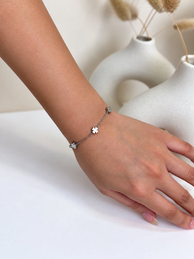 Paired Saphielle Bracelet in silver-tone, worn on the wrist with a slim chain and small four-petal clover charms