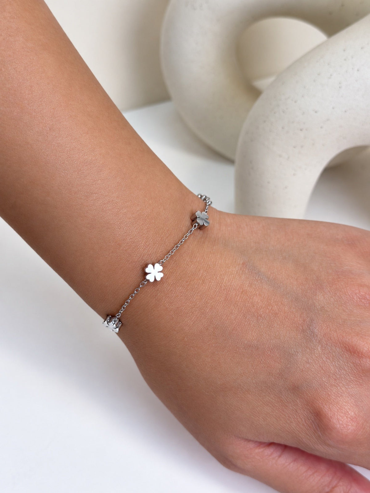 Paired Saphielle Bracelet in silver-tone, close view on the wrist of the fine chain and a four-petal clover charm