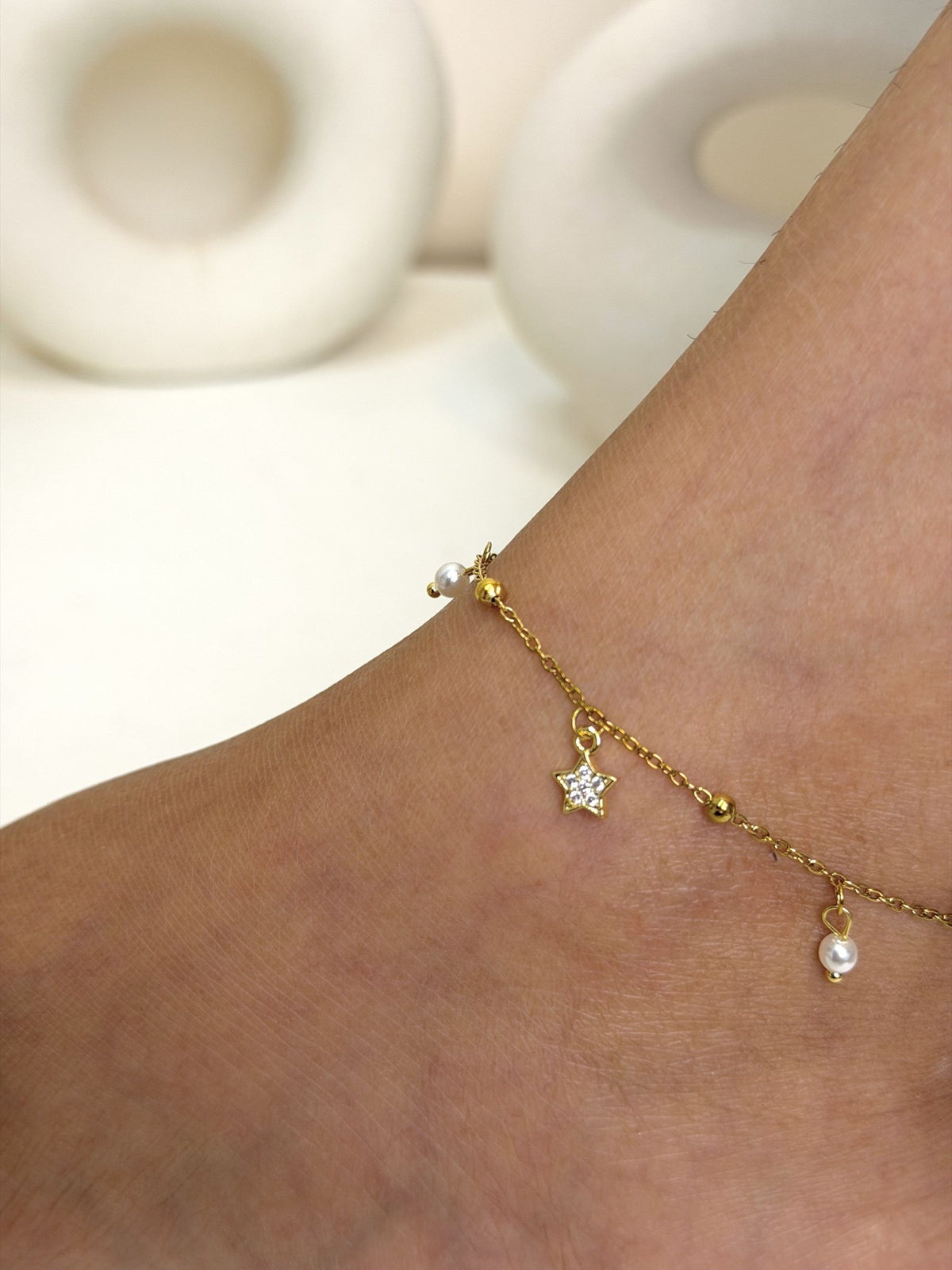 Paired Serelle Anklet in gold-tone, close-up on the ankle showing the star charm and white bead drop