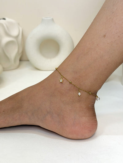 Paired Serelle Anklet in gold-tone, side view on the ankle with a beaded chain, star charm and white bead drops