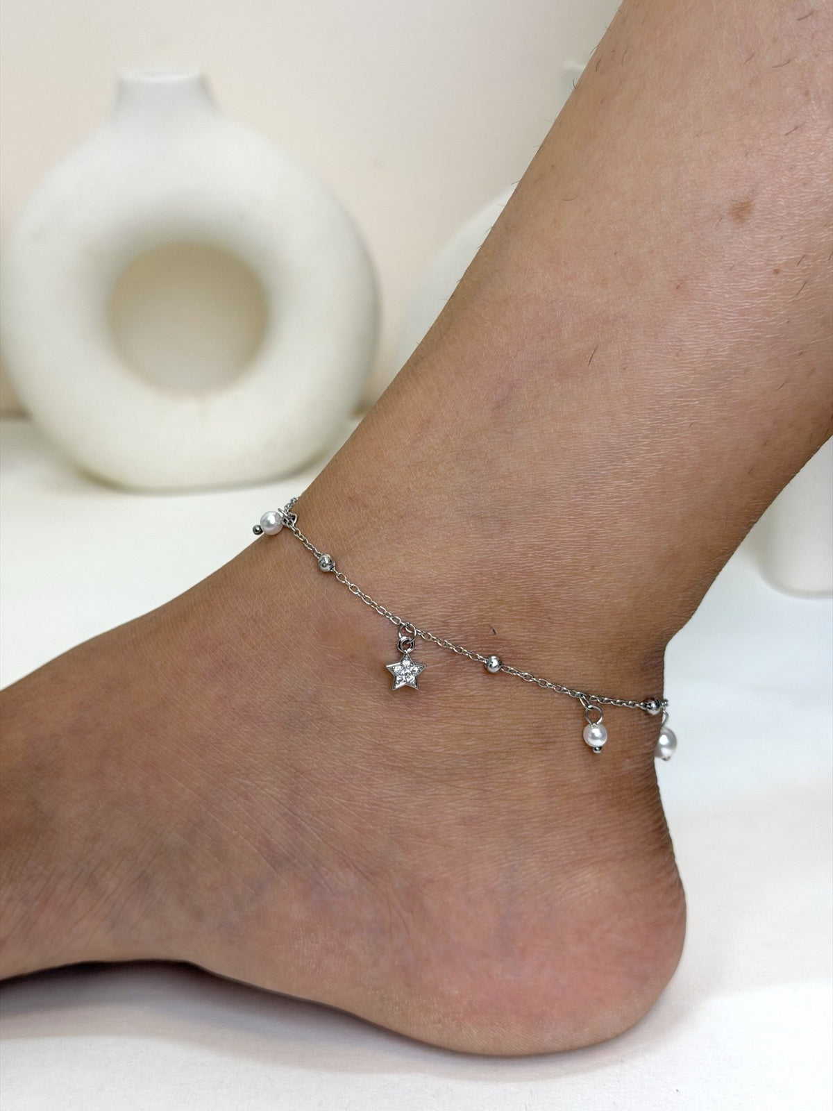 Paired Serelle Anklet in silver-tone, worn on the ankle with a clear-stone star charm and white bead drops