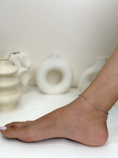 Paired Solène Anklet in silver-tone, worn on the foot and ankle with a fine chain and small ball beads