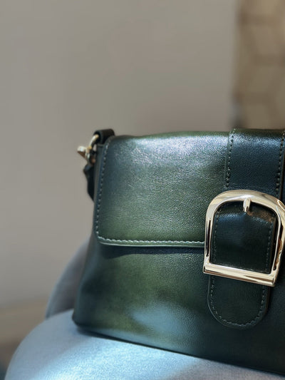 Paired Valora Buckle Sling Bag in deep green, close-up of the buckle, flap and stitched edge