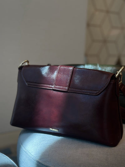 Paired Valora Buckle Sling Bag in deep burgundy red, seen from the back with a stitched flap and the Paired logo at the base