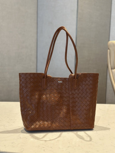Paired Virelle Woven Bag in tan brown, an open-top tote with two rolled handles, shown from the front on a marble table