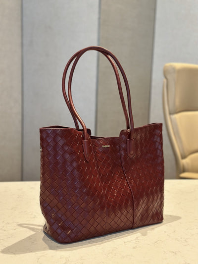 Paired Virelle Woven Bag in maroon, an open-top tote with two rolled handles, shown at a slight angle on a marble table
